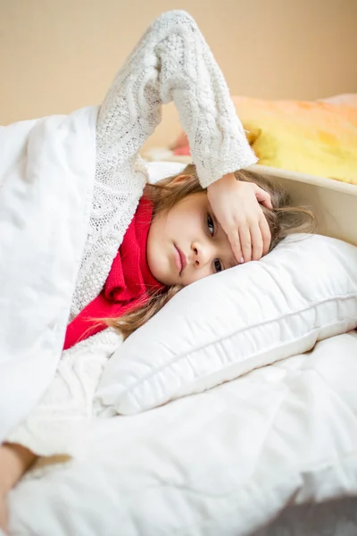 Sick girl lying in bed and holding hand on head — Stock Photo, Image