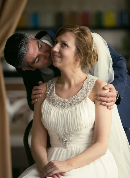 Retrato tonificado de noivo bonito beijando noiva na bochecha sentado — Fotografia de Stock