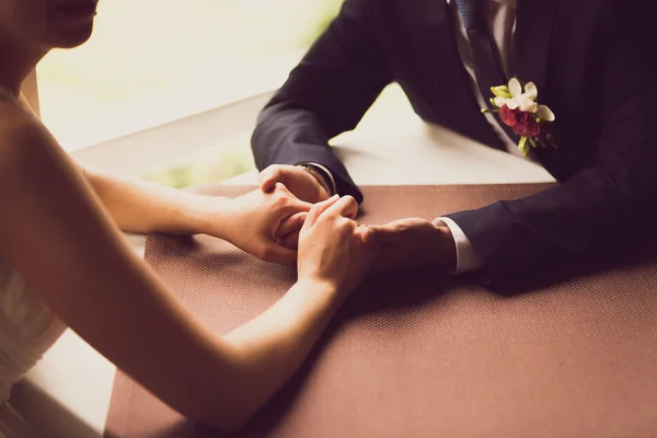 Toned photo of bride and groom holding hands at restaurant — Zdjęcie stockowe