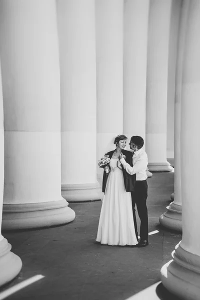 Black and white photo of newlyweds hugging between columns — Stok fotoğraf