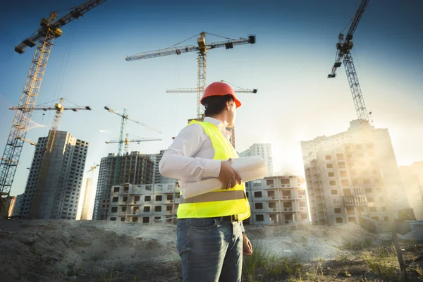 Uomo in hardhat e giacca verde in posa sul cantiere — Foto Stock