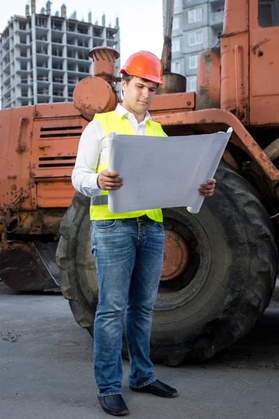 Engineer reading instruction to bulldozer at building site