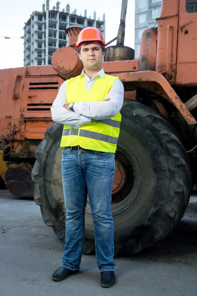 Foreman in helmet posing next to bulldozer with crossed hands — Stock Photo, Image