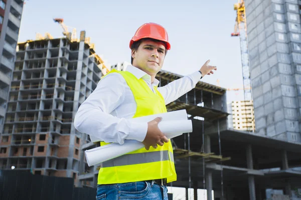 Closeup portrait of architect in hardhat showing building — Φωτογραφία Αρχείου