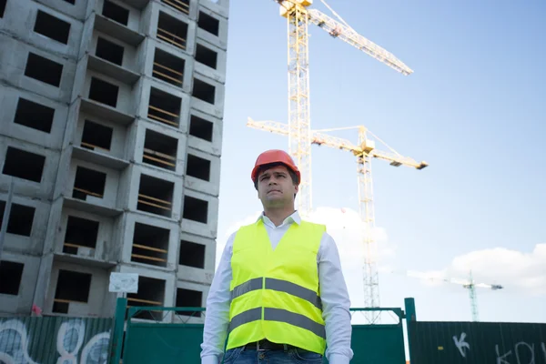 Construction manager posing against cranes and building site — Stock Photo, Image