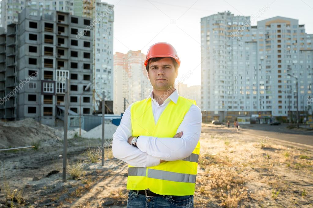 engineer in hardhat posing against building under construction