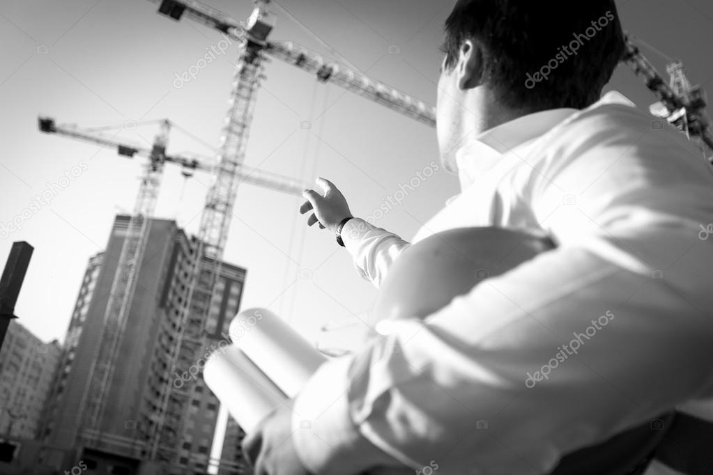 Black and white closeup of engineer pointing at the building