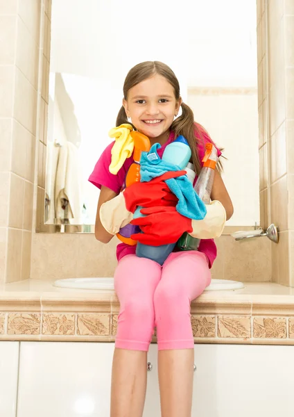 Chica sonriente posando con limpiadores en botellas en el baño — Foto de Stock