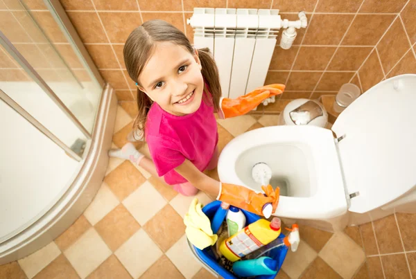 Sorridente menina limpeza banheiro com escova e olhando para a câmera — Fotografia de Stock