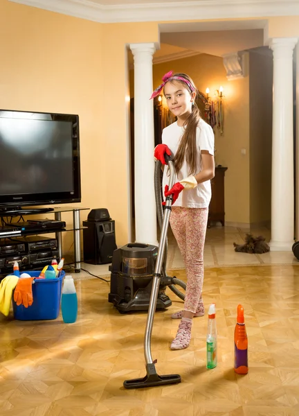 Menina sorrindo posando com aspirador de pó ao fazer a limpeza — Fotografia de Stock