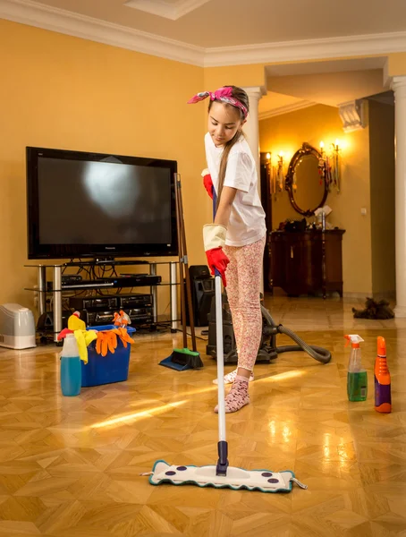 Ganzkörperporträt eines Teenie-Mädchens, das Holzboden mit Tupfer wäscht — Stockfoto