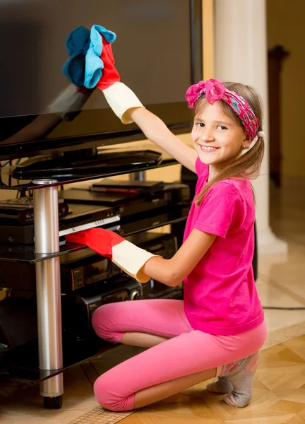 Fille souriante faisant des travaux ménagers un grand écran de télévision de nettoyage — Photo