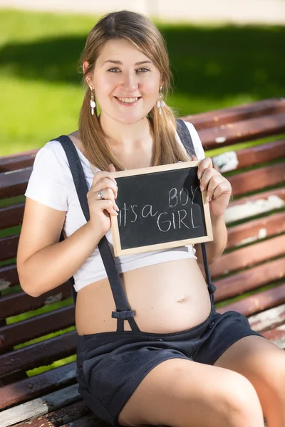 Leende gravid kvinna sitter på bänken och gissa på barnets s — Stockfoto