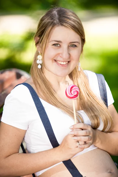 Retrato de mulher grávida sorridente posando com pirulito — Fotografia de Stock