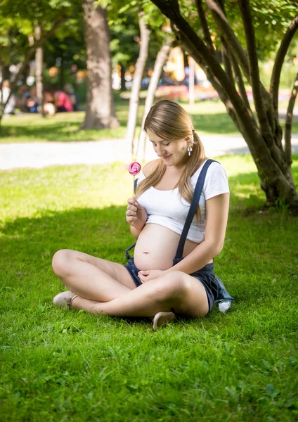 Концептуальный снимок беременной женщины, дающей леденец нерожденному ребенку — стоковое фото