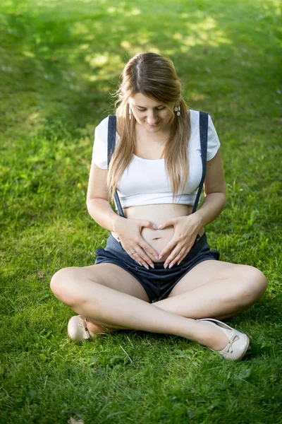 Zwangere vrouw hand in hand in de vorm van hart op buik — Stockfoto