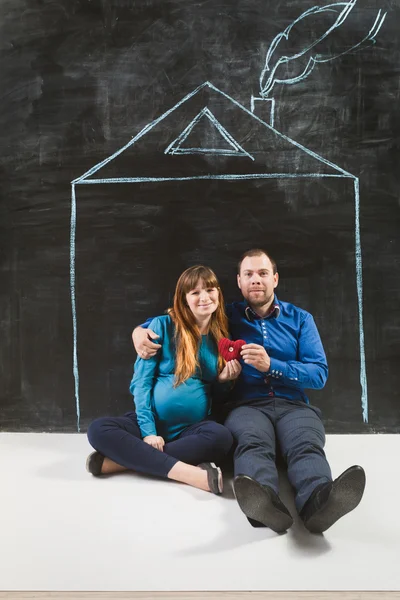 Glückliche Familie posiert auf Kreidetafel gegen Haus gezeichnet — Stockfoto
