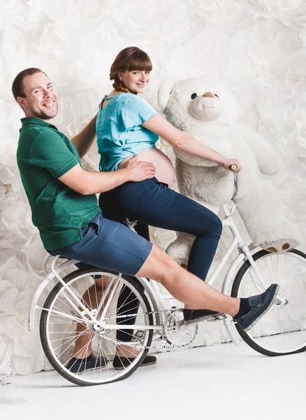 Expectant parents riding on retro bike at studio — Stock Photo, Image