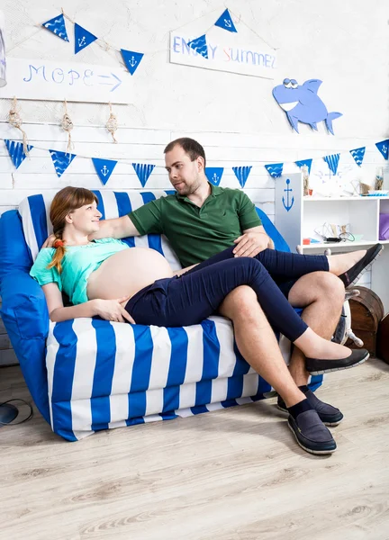 Těhotné ženě a manžel relaxační na gauči v obýváku — Stock fotografie