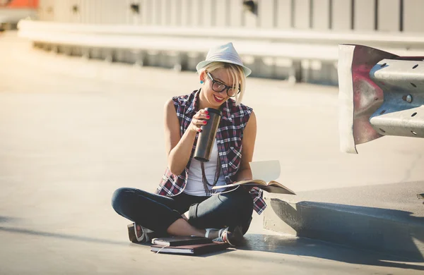 Stylish hipster girl sitting on street and reading book — Stock Photo, Image