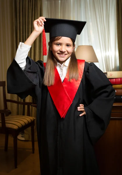 Meisje in afstuderen cap en jurk die zich voordeed op klassieke interieur — Stockfoto