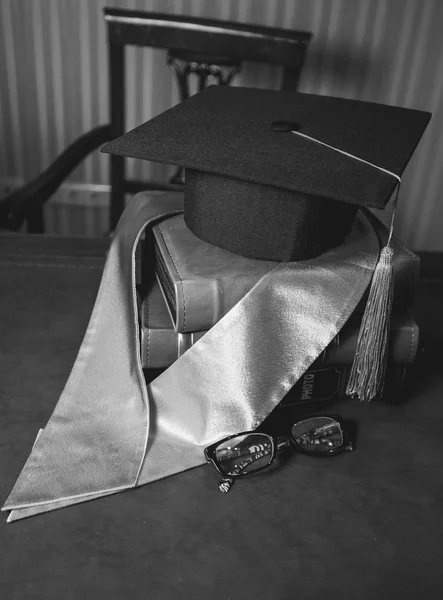 Closeup of graduation hat in ribbon lying on pile of books — Stock Photo, Image