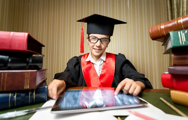 Menina sorridente na tampa de graduação usando tablet digital na biblioteca — Fotografia de Stock