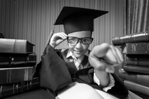 Retrato de menina em boné de graduação e vestido apontando para a câmera — Fotografia de Stock