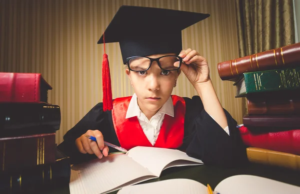 Genius girl in graduation cap looking through eyeglasses at came — Stock Photo, Image