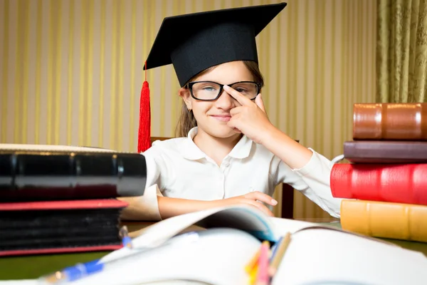 Retrato de chica inteligente en gorra de graduación sosteniendo gafas —  Fotos de Stock