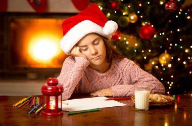 Noel Baba'ya mektup yazarken sevimli kız uyuya