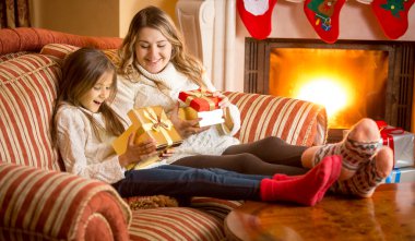 Anne ve kızı firepla yanında/açma Noel hediyeleri