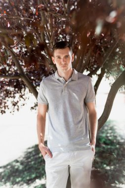 şık delikanlı kırmızı yaprakları ile ağacın altında poz