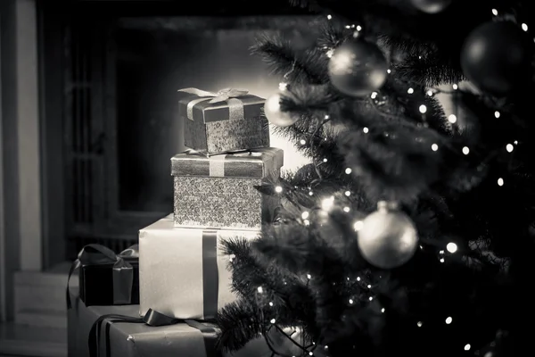 Monochromes Foto von Weihnachtsgeschenken auf dem Boden neben dekorierten f — Stockfoto