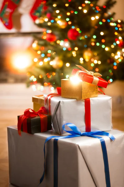 Geschenkdozen onder kerstboom naast de open haard in de woonkamer — Stockfoto