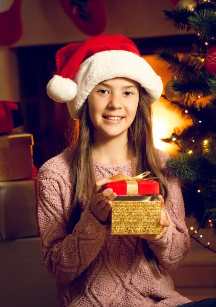 Retrato de cerca de una chica sonriente en una caja de regalo con tapa de Santa —  Fotos de Stock