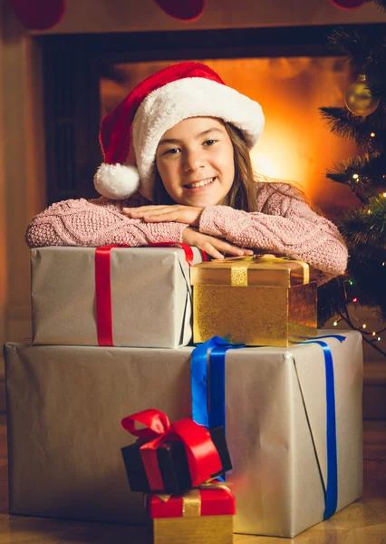 Nettes lächelndes Mädchen posiert mit Weihnachtsgeschenken am Kamin — Stockfoto