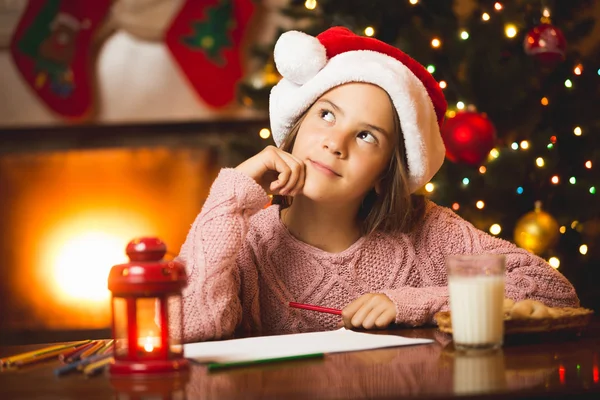 Bonito menina pensando de carta para Santa na sala de estar — Fotografia de Stock