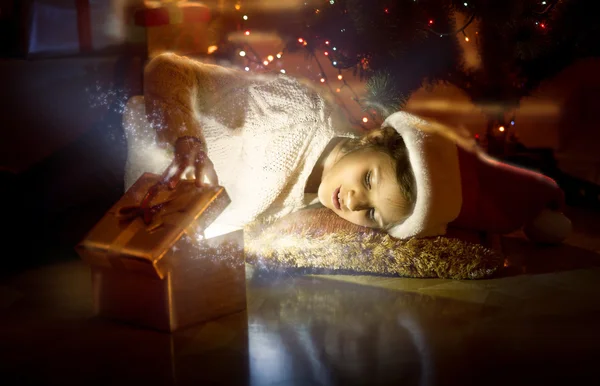 Sorrindo menina deitada no chão e olhando para dentro de magia brilhante — Fotografia de Stock