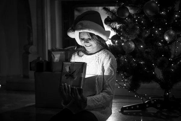 Ragazza sorridente guardando dentro di scatola regalo incandescente alla vigilia di Natale — Foto Stock