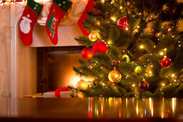 Christmas background of table against Christmas tree and firepla — Stock Photo, Image