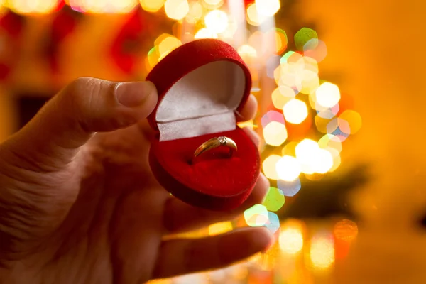 Hombre presentando anillo de oro en caja contra decorado de Navidad tr — Foto de Stock