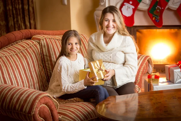 Mère et fille posant à la cheminée avec boîte cadeau à Noël — Photo