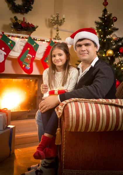 Hombre y chica relajarse en el sofá en la chimenea en la víspera de Navidad — Foto de Stock