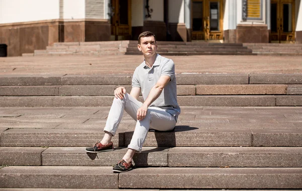 Elegante hombre sentado en escaleras de piedra en un día soleado —  Fotos de Stock