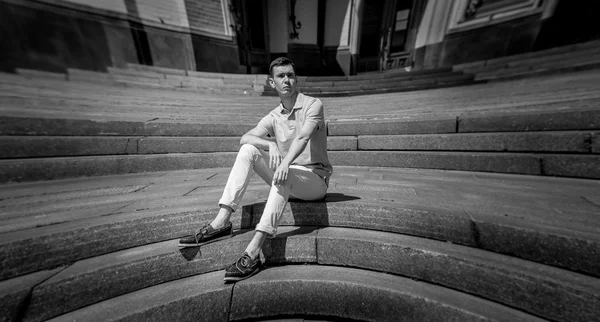 Черно-белый снимок стильного мужчины, отдыхающего на каменной лестнице — стоковое фото