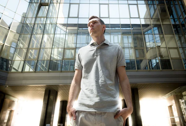 Young man posing against glass wall at business center — Stock Photo, Image