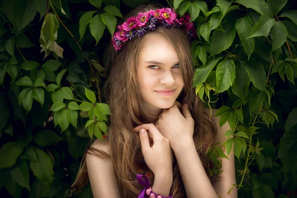 Beautiful young woman posing under big bushes at park — Stock Photo, Image