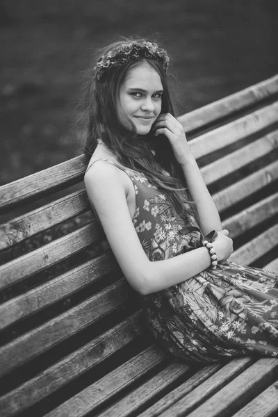 Monochrome portrait of cute woman sitting on bench at park — Stock Photo, Image