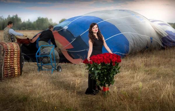 Schöne Frau posiert mit Rosenstrauß am Heißluftballon — Stockfoto